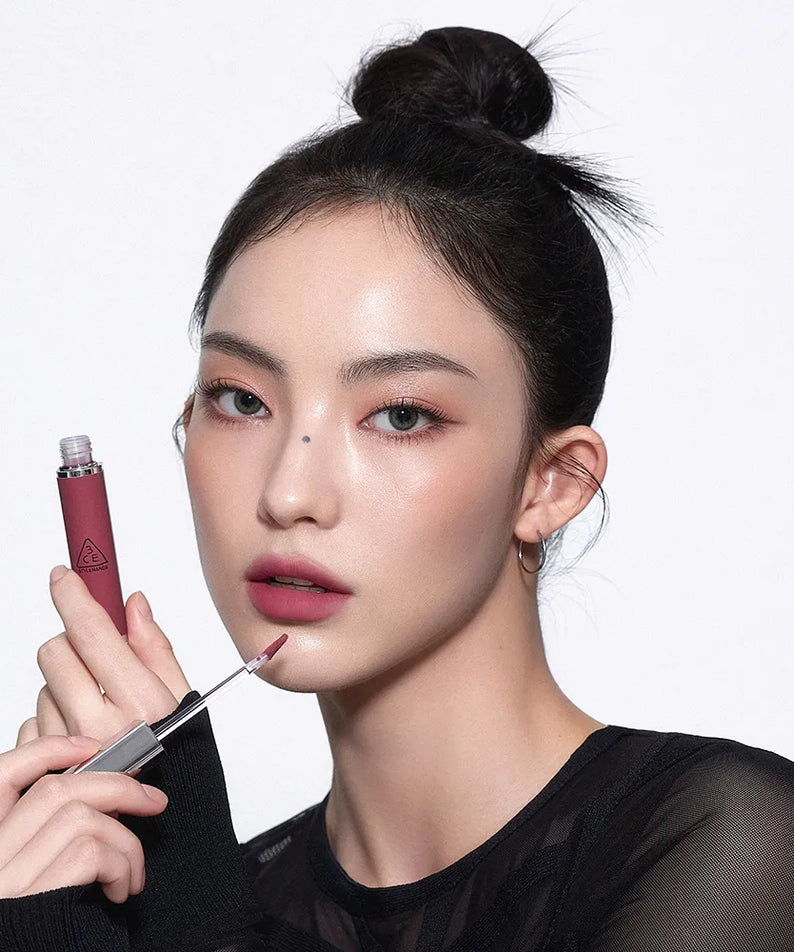 3CE Hazy Lip Clay, rouge à lèvres flacon sur fond clair, maquillage smoky; main appliquant le produit, marque 3CE visible.