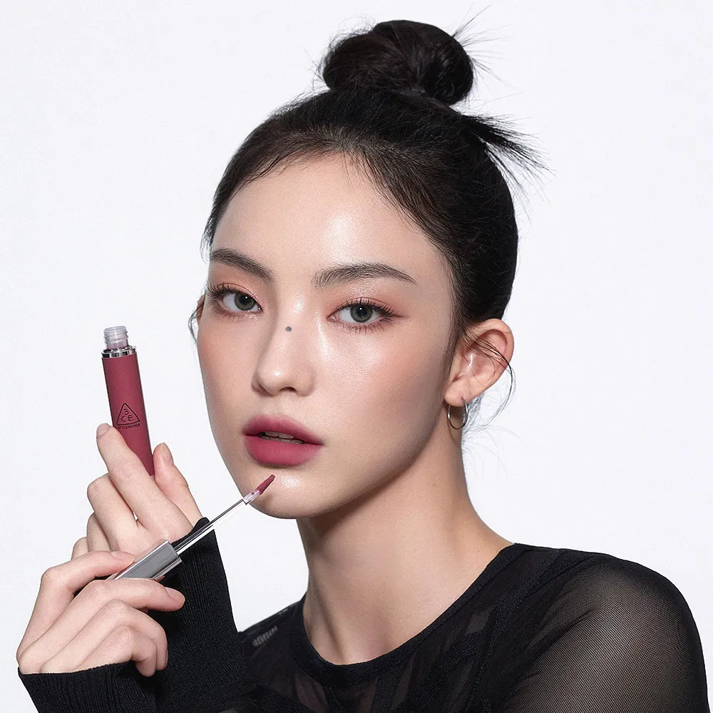 3CE Hazy Lip Clay, rouge à lèvres flacon sur fond clair, maquillage smoky; main appliquant le produit, marque 3CE visible.