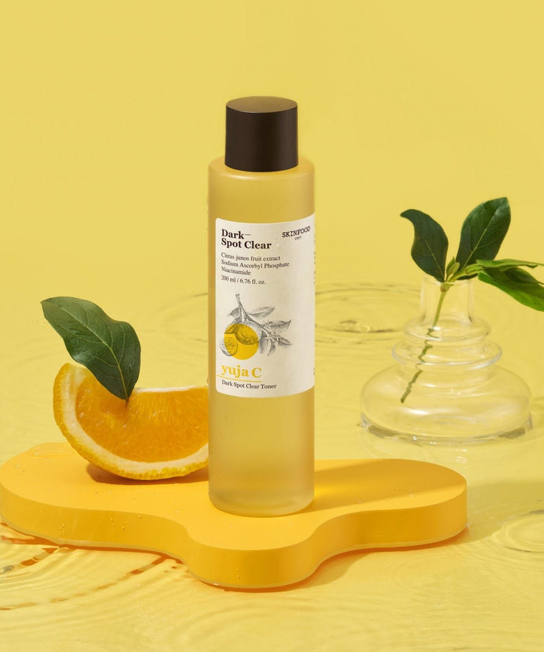 SKINFOOD Yuja C Dark Spot Clear Toner 200ml de SKINFOOD, flacon jaune sur fond jaune, agrumes et feuilles en contexte beauté.