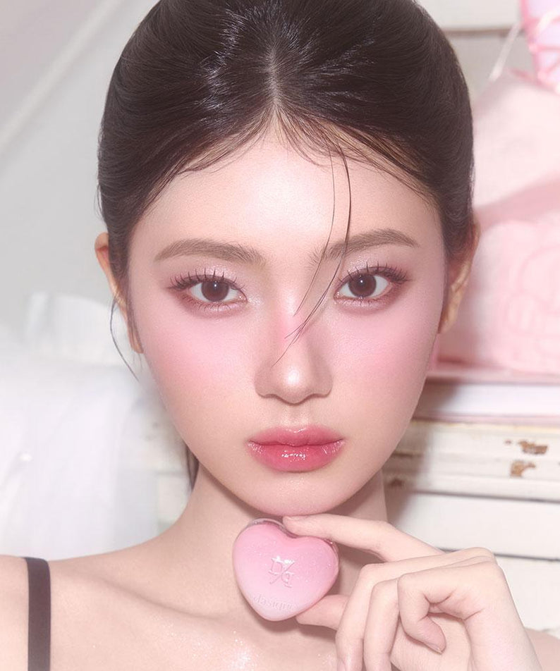 Femme tenant un DASIQUE Daisy Candy Rolling Pot rose en forme de cœur. Produit de beauté élégant pour un maquillage raffiné.