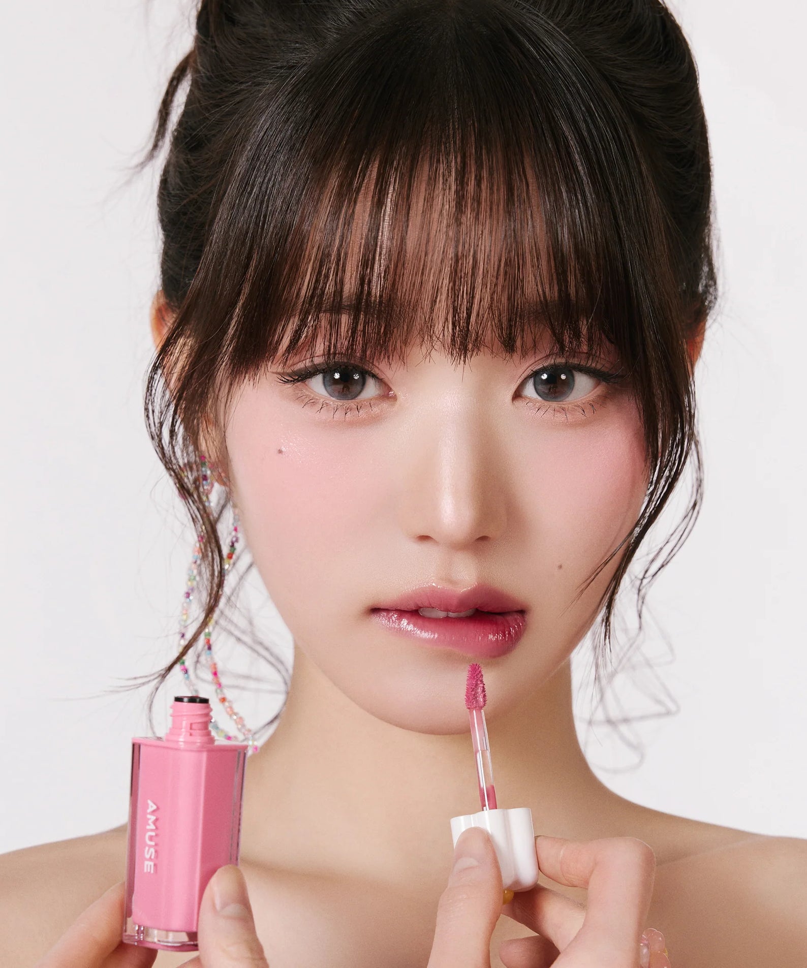 AMUSE Dew Tint de la marque AMUSE, sur fond clair, maquillage rosé en gros plan avec applicateur sur visage