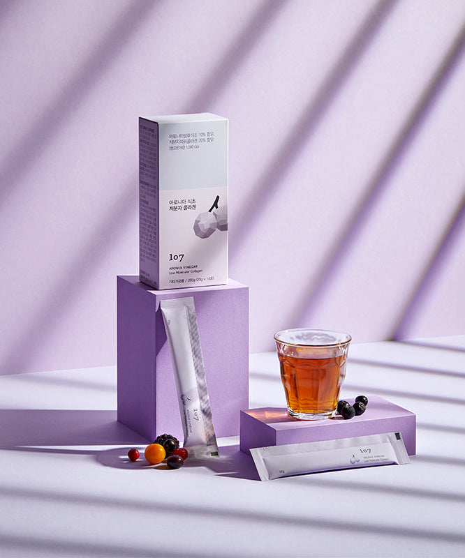 Image du produit 107 Aronia Vinegar Low Molecular Collagen 20g x 14 Packets, présenté avec une boisson et des baies sur un fond violet.