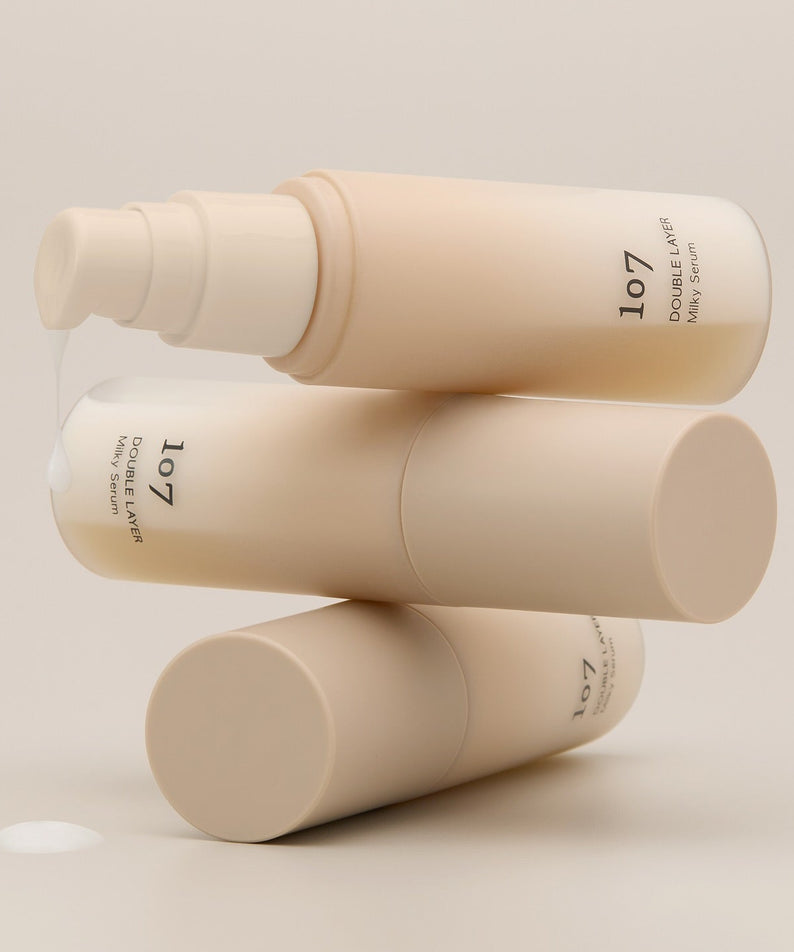 Décrivez l'image en français : 107 Double Layer Milky Serum 50ml, flacons crème beige de la marque 107 sur fond clair.
