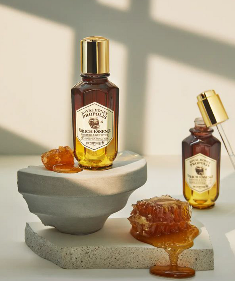 SKINFOOD Royal Honey Propolis Enrich Essence 50ml, flacon doré et miel sur support minéral en studio, marque SKINFOOD