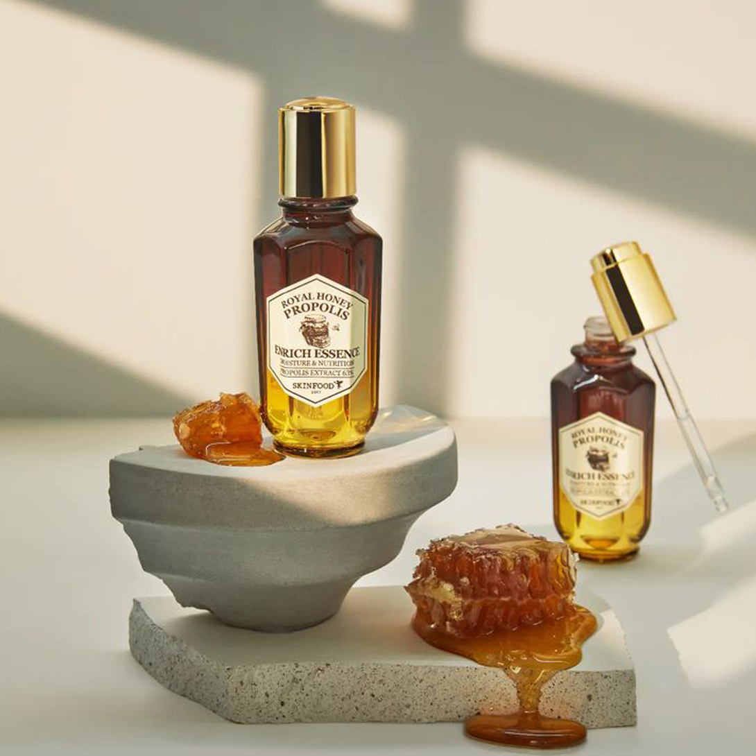 SKINFOOD Royal Honey Propolis Enrich Essence 50ml, flacon doré et miel sur support minéral en studio, marque SKINFOOD