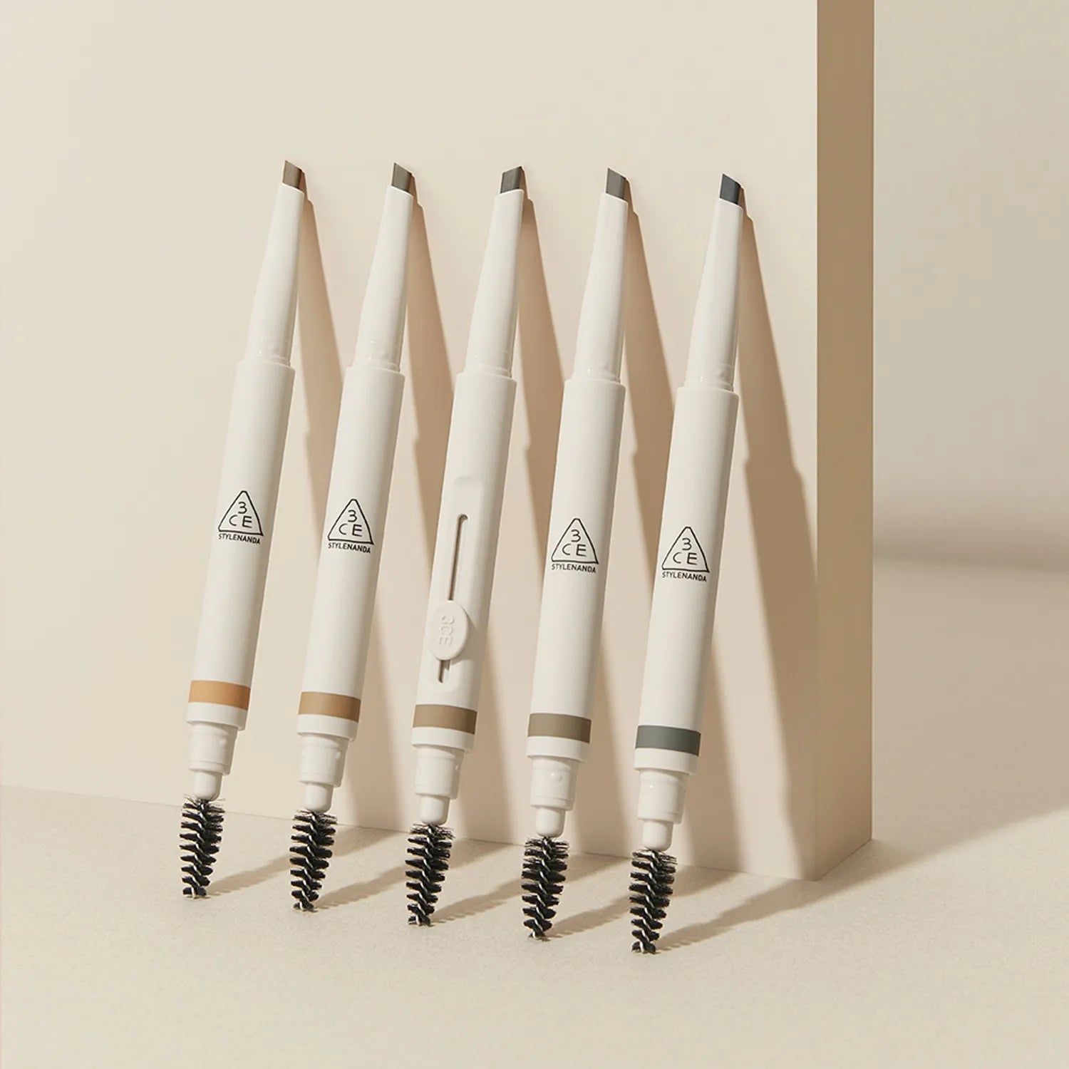 3CE Easy Brow Designing Pencil : crayons sourcils 3CE sur fond beige, présentation visuelle maquillage