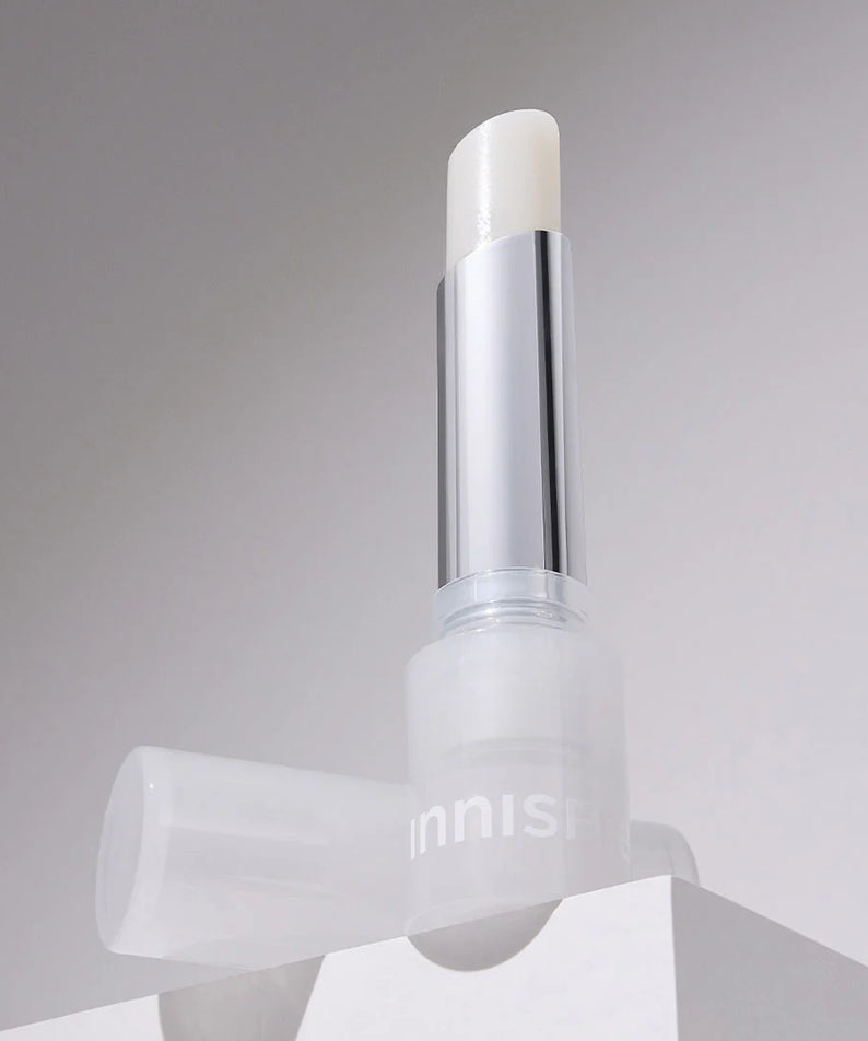 INNISFREE Dewy Treatment Lip Balm 3.2g, baume à lèvres Innisfree sur fond clair, packaging blanc et argenté.