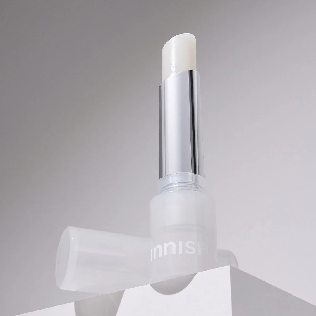 INNISFREE Dewy Treatment Lip Balm 3.2g, baume à lèvres Innisfree sur fond clair, packaging blanc et argenté.