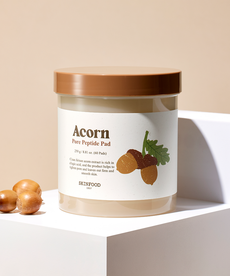 SKINFOOD Acorn Pore Peptide Pad 60 sheets, pot de soin SKINFOOD sur socle blanc, décor noisettes et feuilles, ambiance beige.