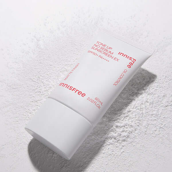 INNISFREE Tone Up Watering Sunscreen 60ml, tube de crème solaire éclaircissante Innisfree sur fond texturé blanc