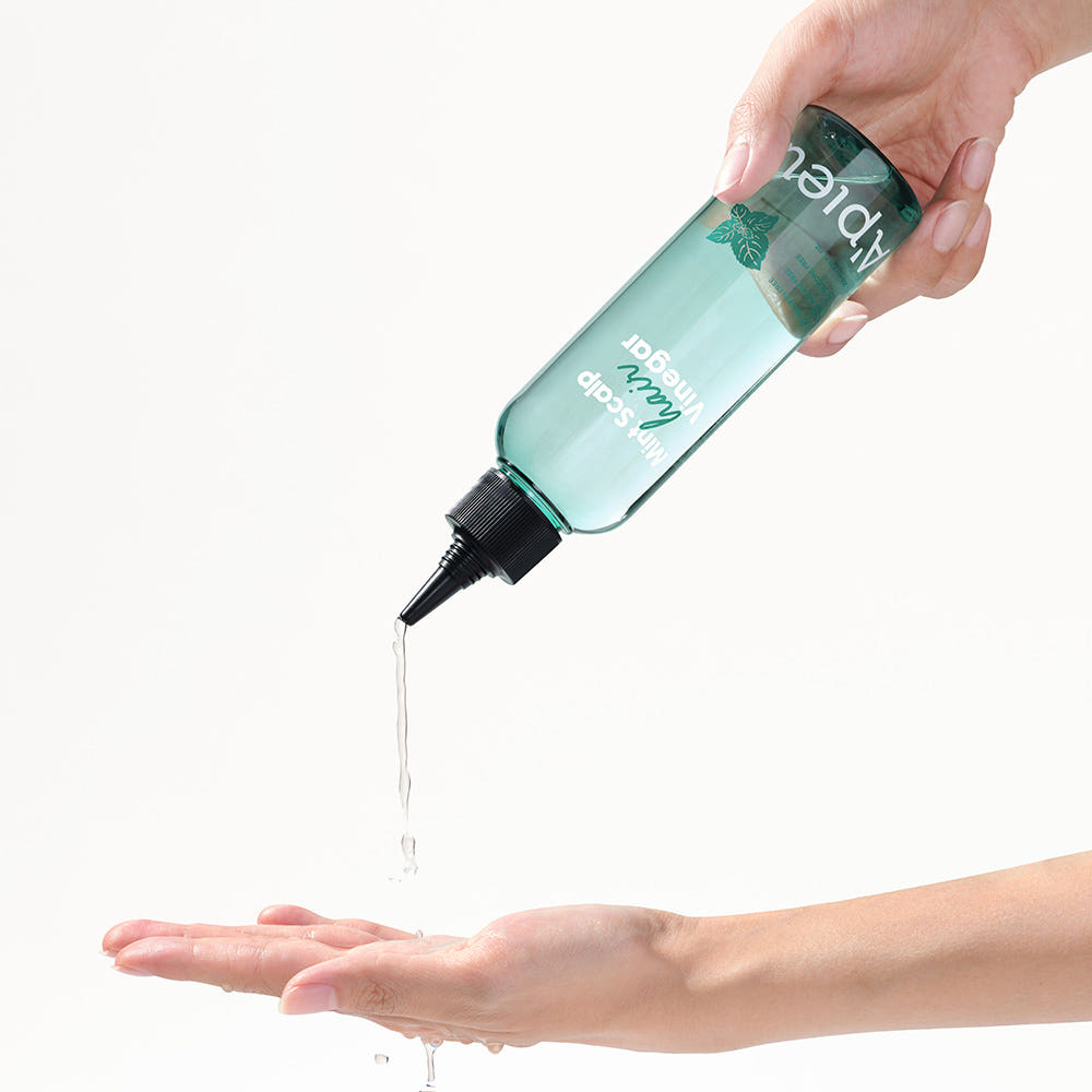 A'PIEU Mint Scalp Hair Vinegar 200ml : la main verse la solution aux huiles sur la peau, marque A'PIEU, fond clair.