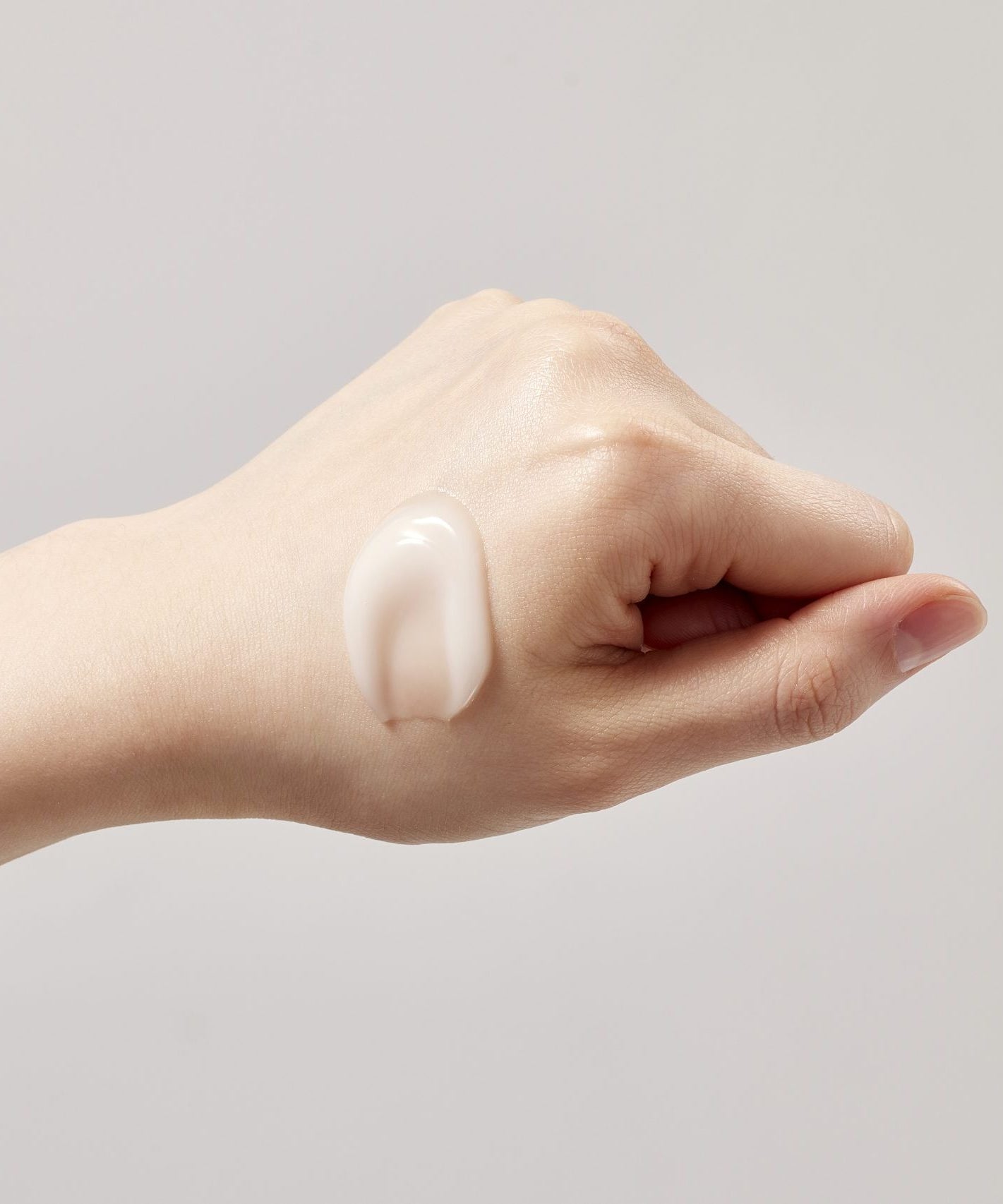 SKINFOOD Acorn Pore Peptide Cream 70ml sur peau, marque et texture crème, main appliquant sur fond clair.