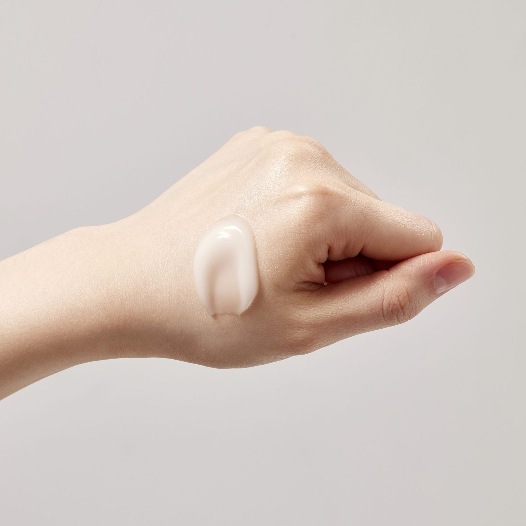 SKINFOOD Acorn Pore Peptide Cream 70ml sur peau, marque et texture crème, main appliquant sur fond clair.