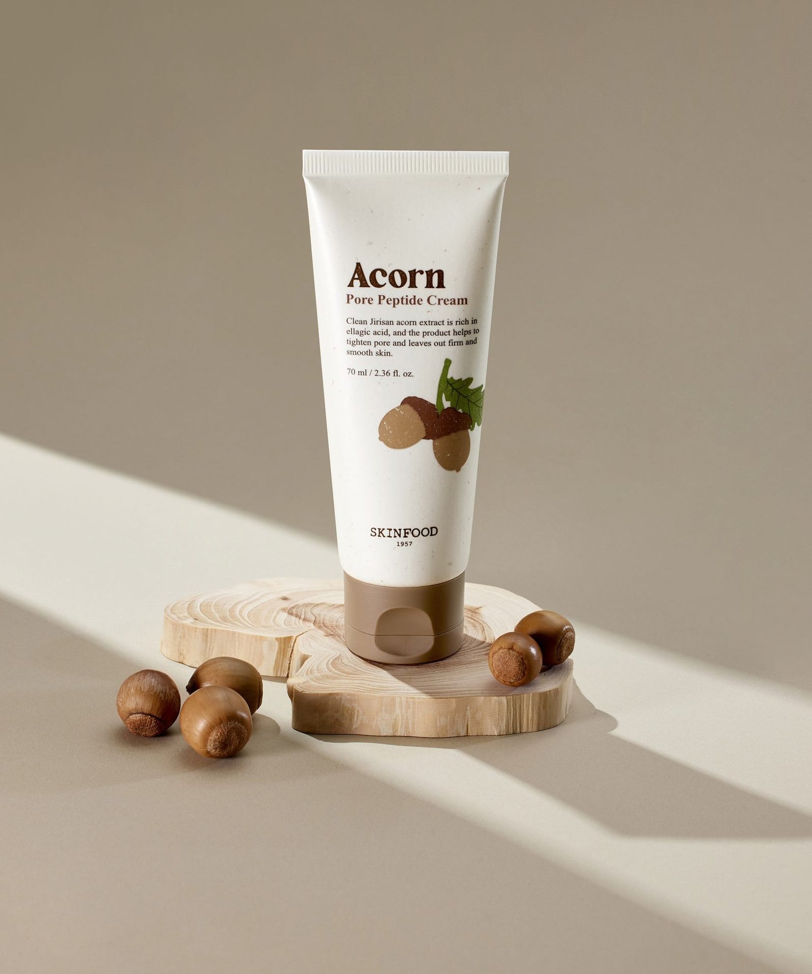 SKINFOOD Acorn Pore Peptide Cream 70ml : tube crème sur socle bois, noisettes, éclairage doux, style skincare.