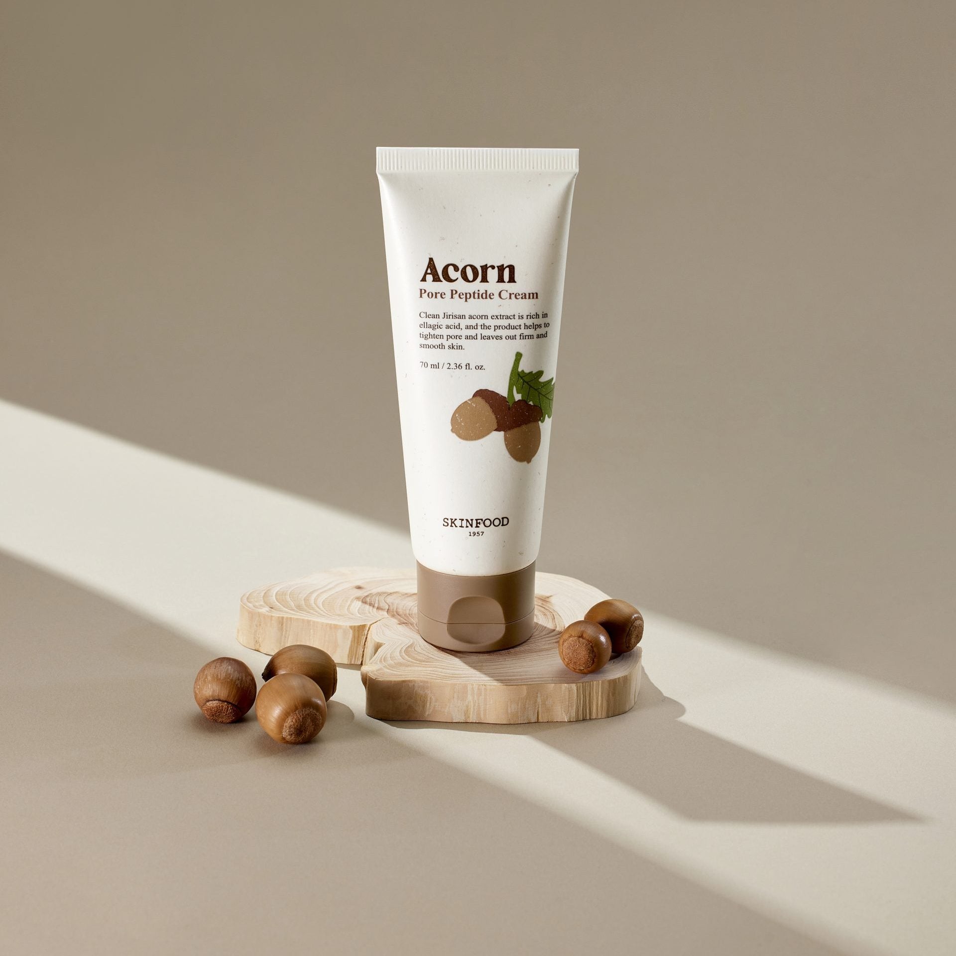 SKINFOOD Acorn Pore Peptide Cream 70ml : tube crème sur socle bois, noisettes, éclairage doux, style skincare.