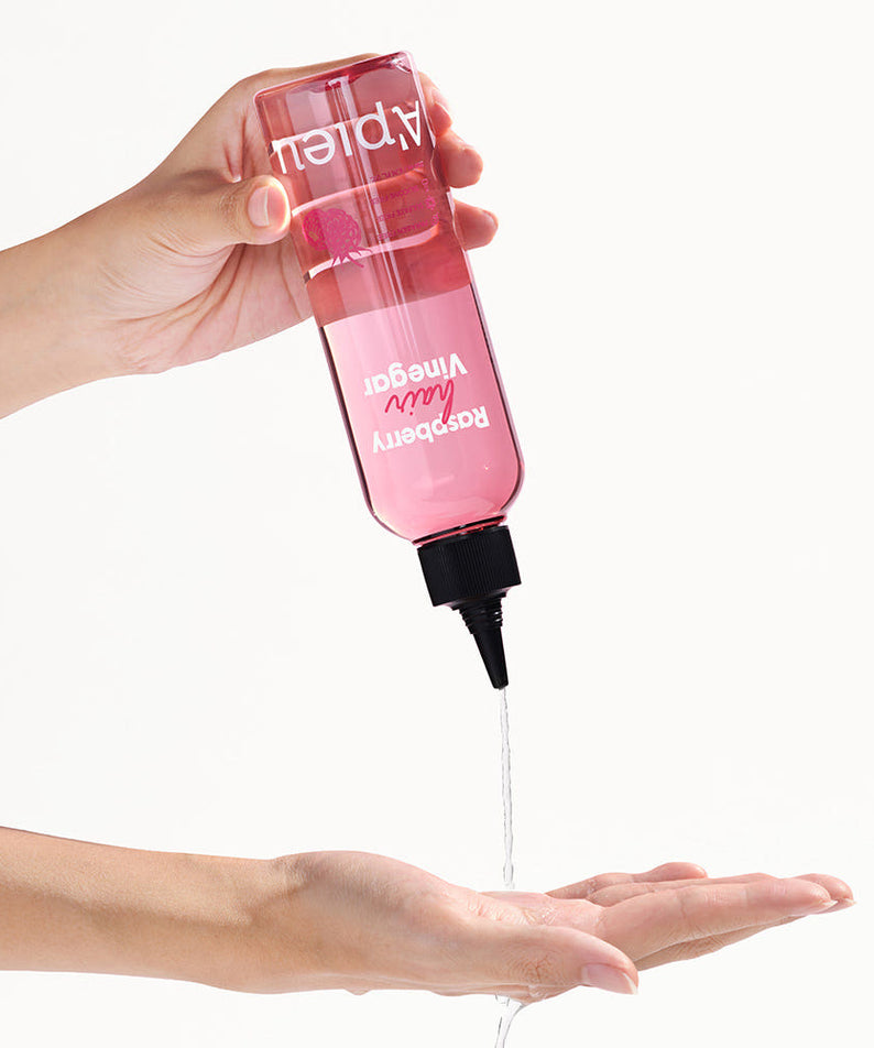 A'PIEU Raspberry Hair Vinegar 200ml, marque A'PIEU, flacon tenu sur fond clair, cheveux: application gouttes sur la main
