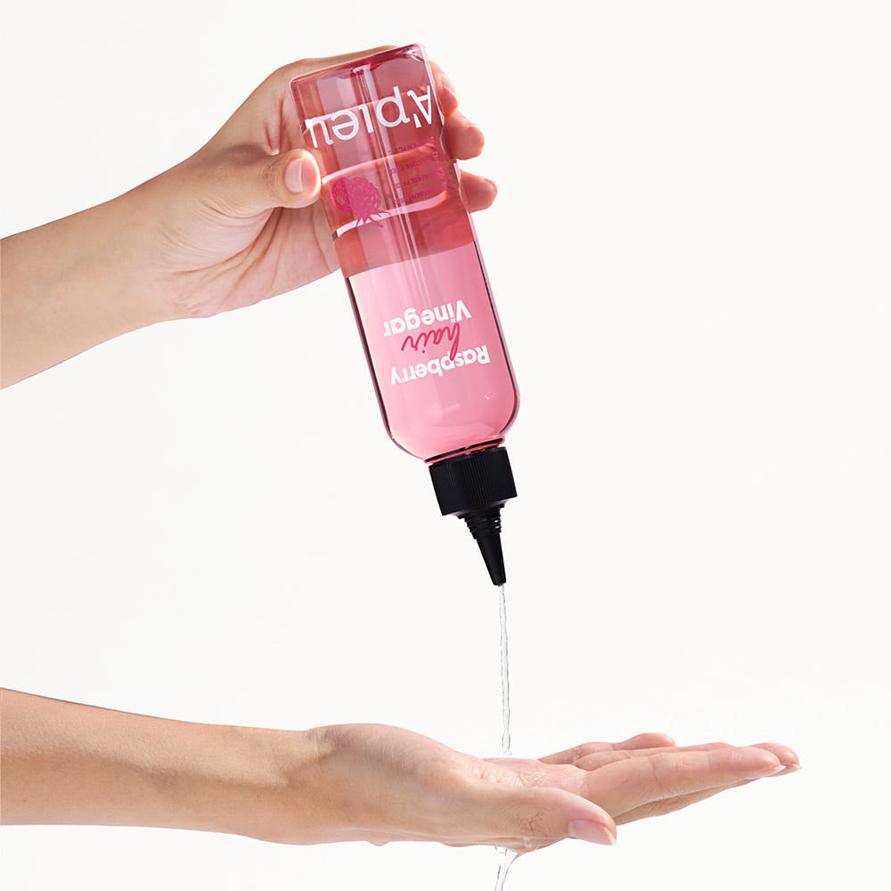 A'PIEU Raspberry Hair Vinegar 200ml, marque A'PIEU, flacon tenu sur fond clair, cheveux: application gouttes sur la main