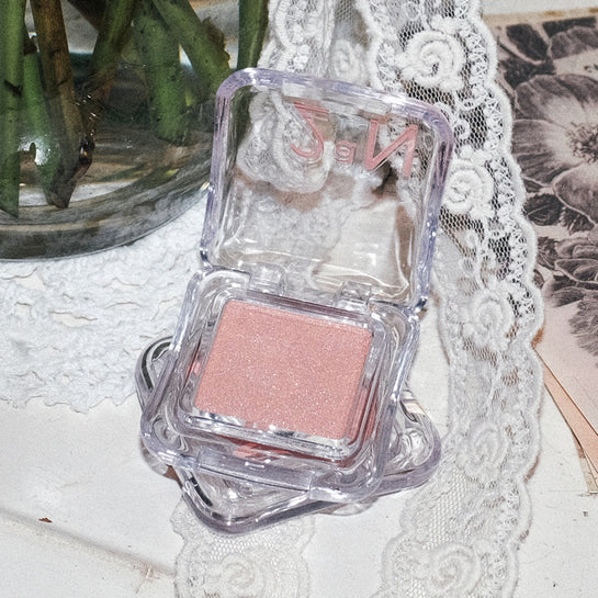 2AN Pure Glash Highlighter de la marque 2AN, sur fond déco avec dentelle et fleurs, vue produit maquillage.