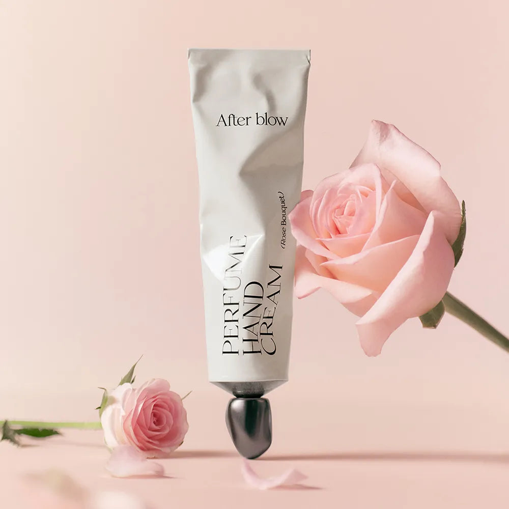 AFTER BLOW Perfume Hand Cream 50ml, main crème parfumée de la marque After blow, posée avec une rose et fleurs sur fond clair.