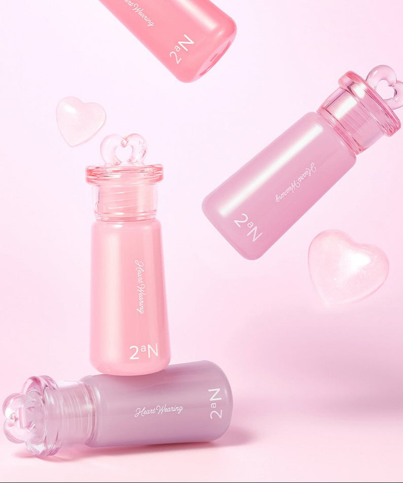 2AN Heart Wearing Liquid Cheek 4.4g posé sur fond rose avec des flacons en forme de cœur, maquillage visage élégant et moderne.