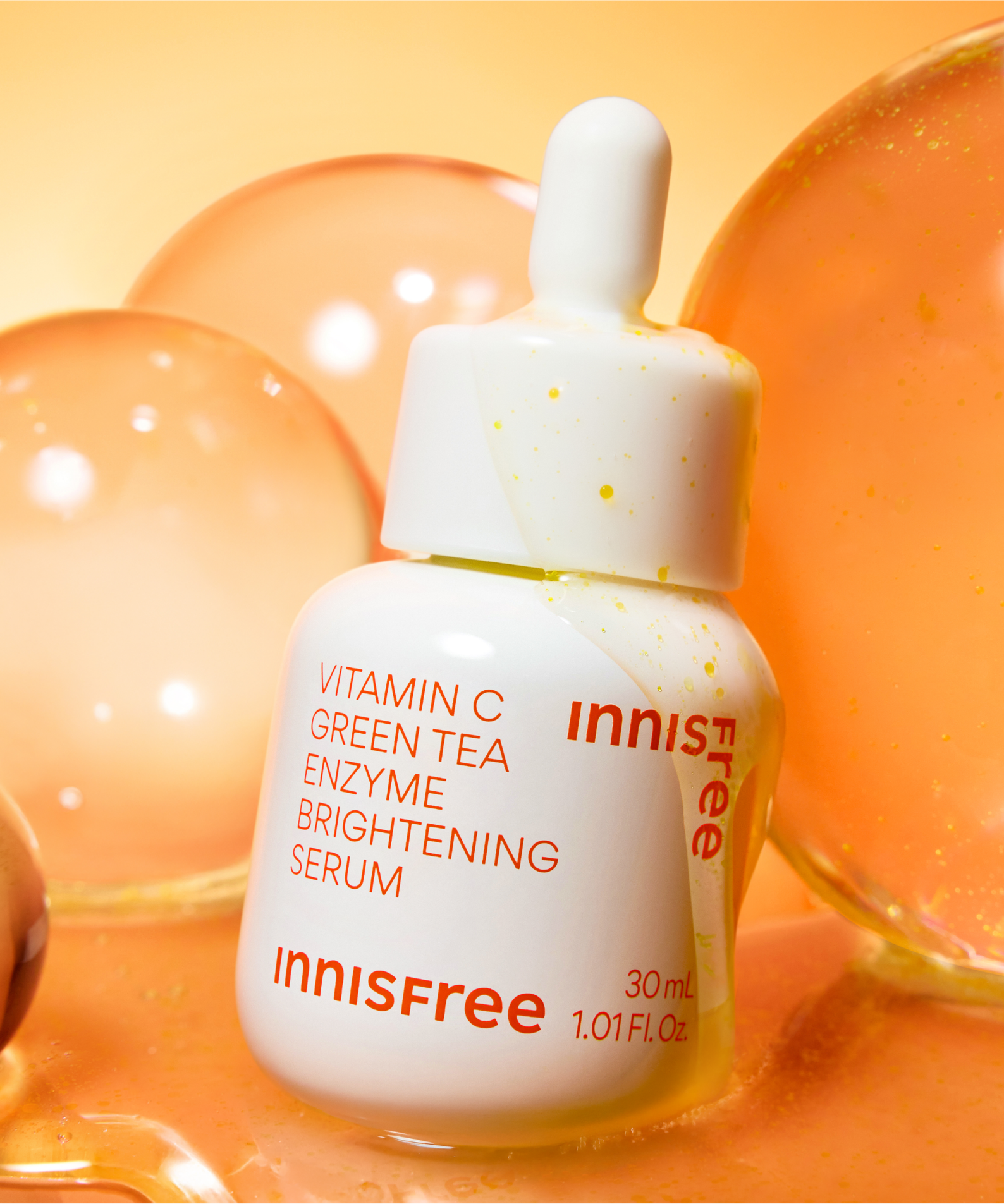 INNISFREE Vitamin C Green Tea Enzyme Brightening Serum de la marque Innisfree sur fond orange, bulles, flacon 30ml