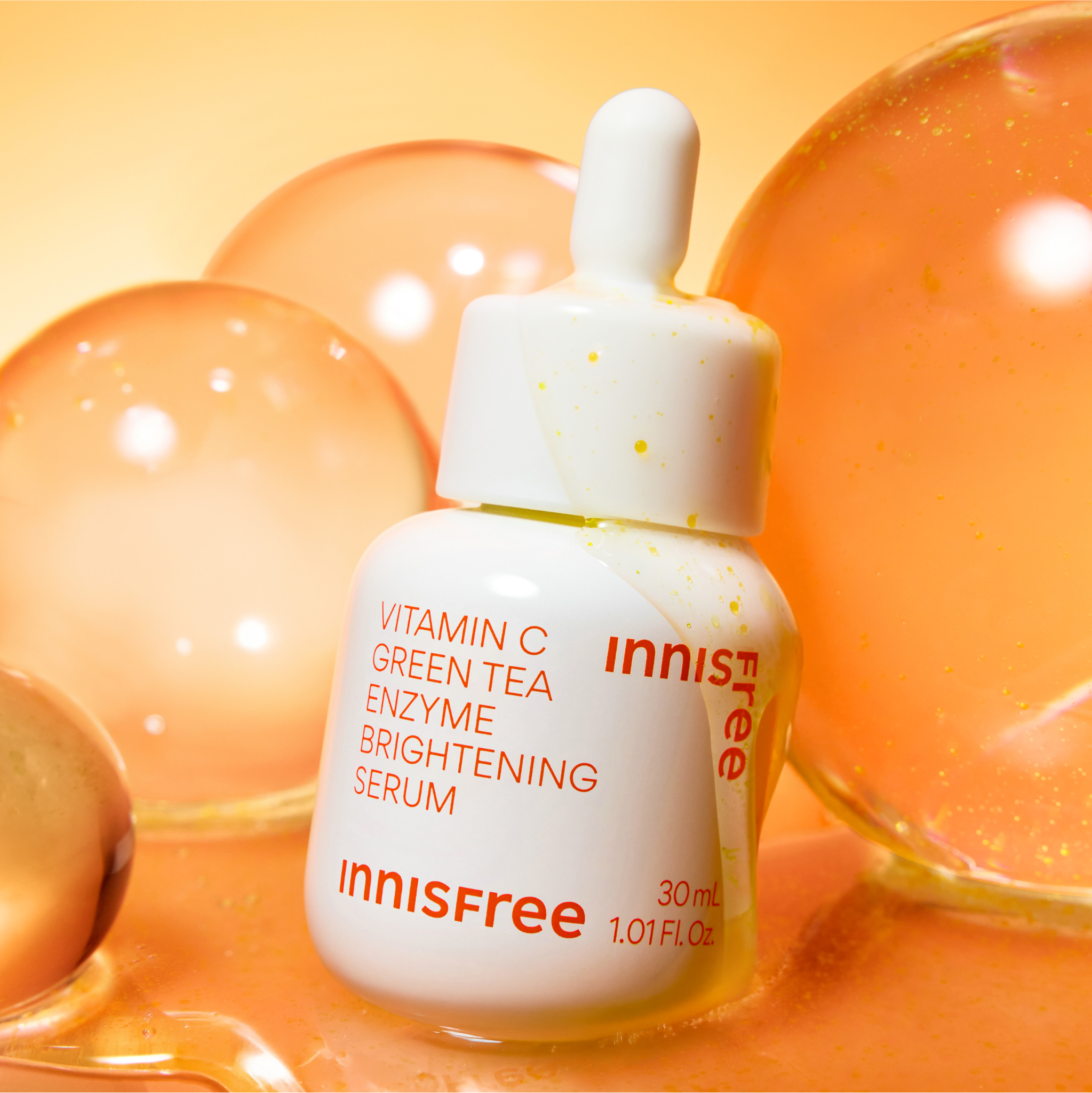 INNISFREE Vitamin C Green Tea Enzyme Brightening Serum de la marque Innisfree sur fond orange, bulles, flacon 30ml