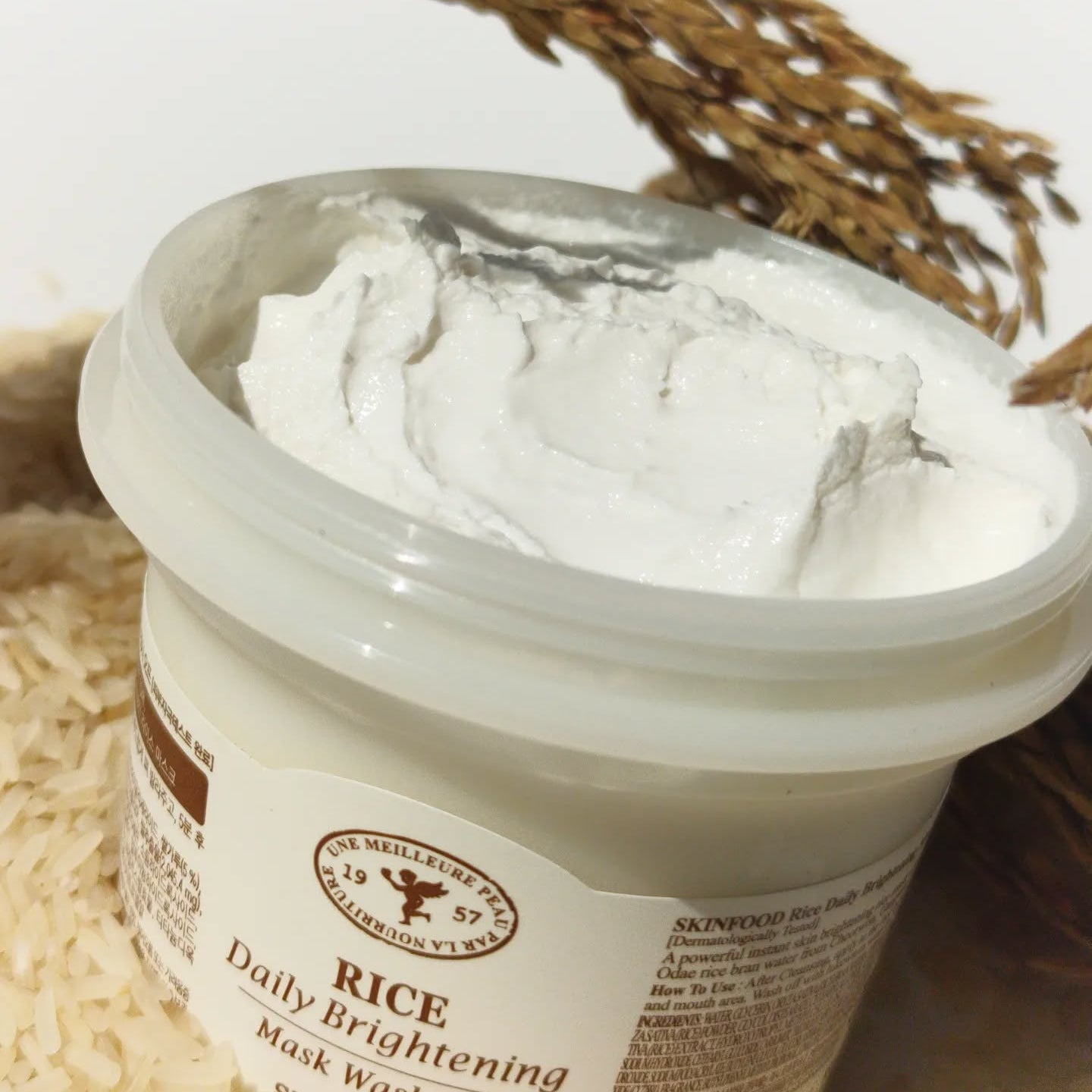 SKINFOOD Rice Daily Brightening Mask Wash Off 210g : masque crème blanc dans un pot, riz et herbes en fond, marque.