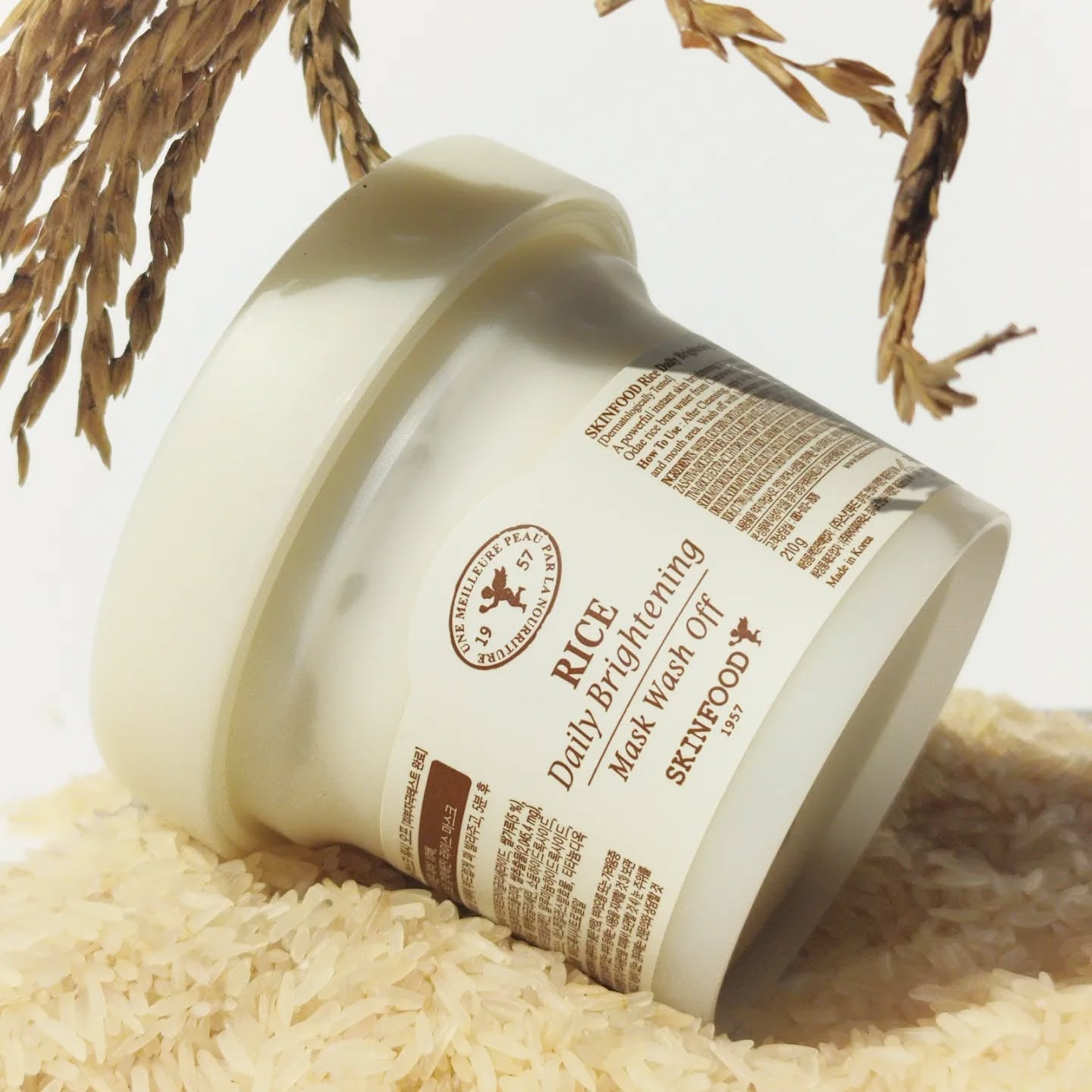 SKINFOOD Rice Daily Brightening Mask Wash Off 210g de SKINFOOD, pot crème sur riz, décor naturel (feuilles séchées).