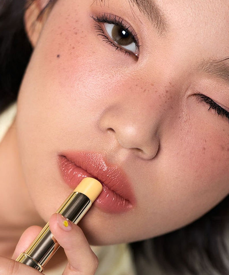 3CE Color Baker Glazy Lip Glow : femme applique un baume luisant sur lèvres, gros plan maquillage