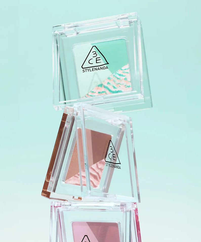 3CE Color Grid Eyeshadow, boîte transparente avec palette de fards colorés 3CE sur fond bleu clair