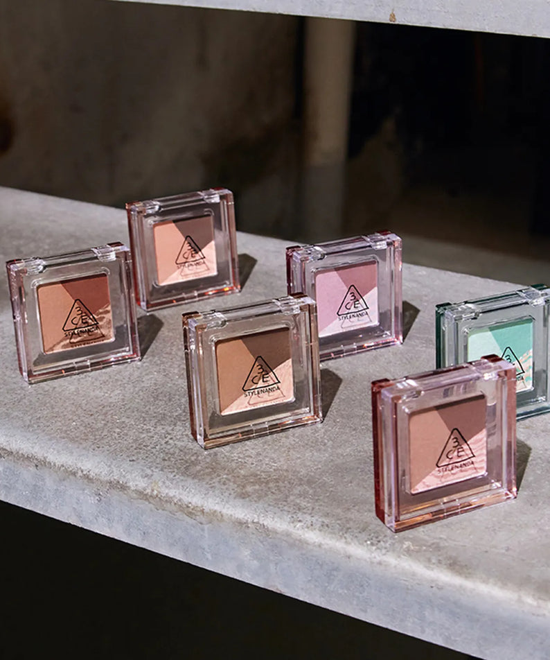 3CE Color Grid Eyeshadow : palette d’ombres dans un boîtier transparent, teintes nude et rose, présentation sur étagère.