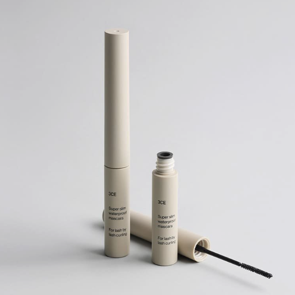 Décris l'image en français : 3CE Super Slim Waterproof Mascara, flacon et brosse sur fond clair, marque 3CE.