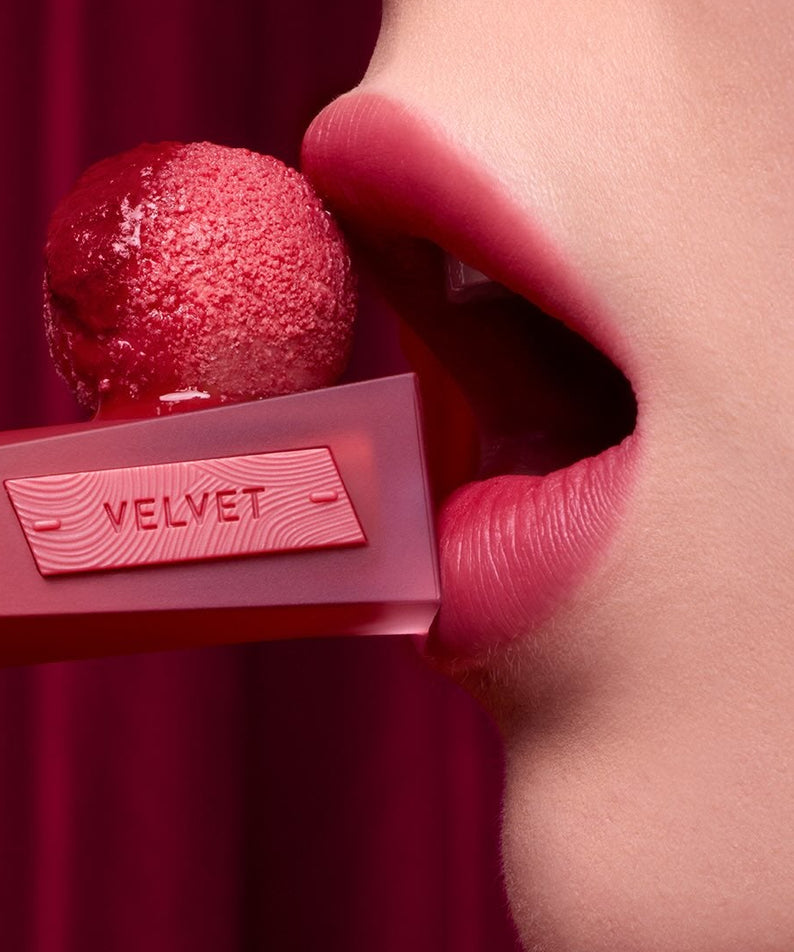 3CE Velvet Lip Tint Plush, bouche au rouge velours sur fond bordeaux, produit 3CE et texture satinée en gros plan.