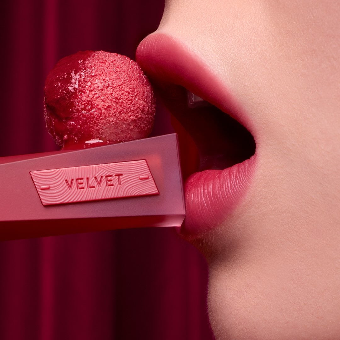 3CE Velvet Lip Tint Plush, bouche au rouge velours sur fond bordeaux, produit 3CE et texture satinée en gros plan.