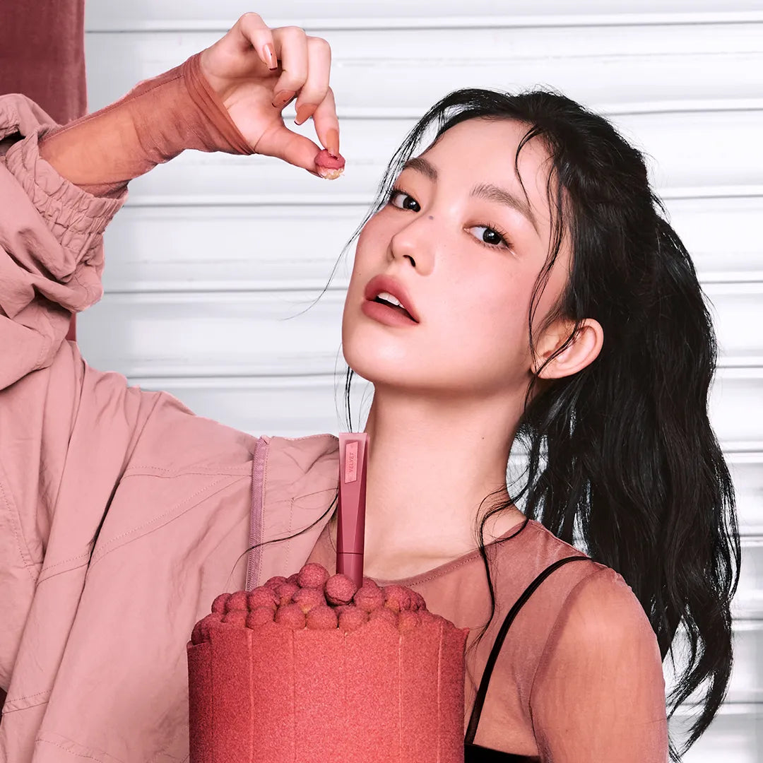 3CE Velvet Lip Tint Plush de 3CE, maquillage sur fond clair, appliqué sur les lèvres d’une jeune femme.