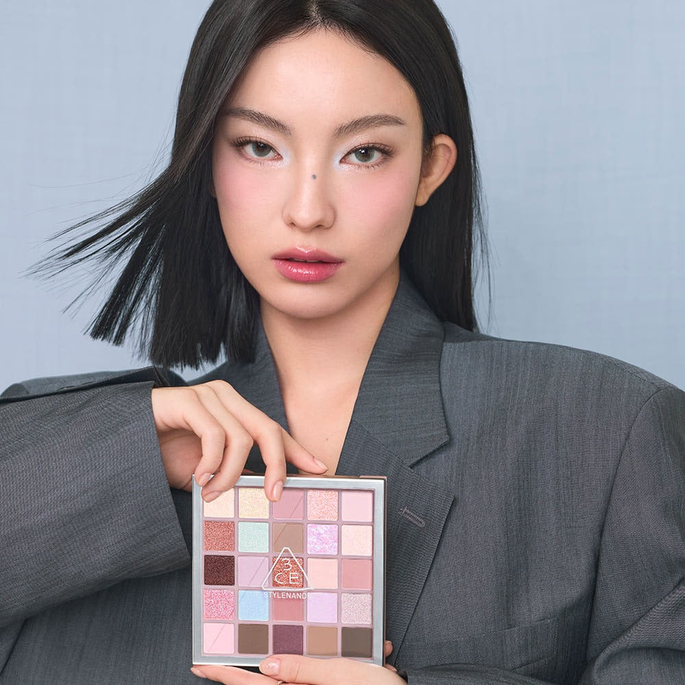 3CE XL Eyeshadow Palette : femme maquillée tenant la palette, sur fond bleu clair, lumière douce, vue rapprochée.