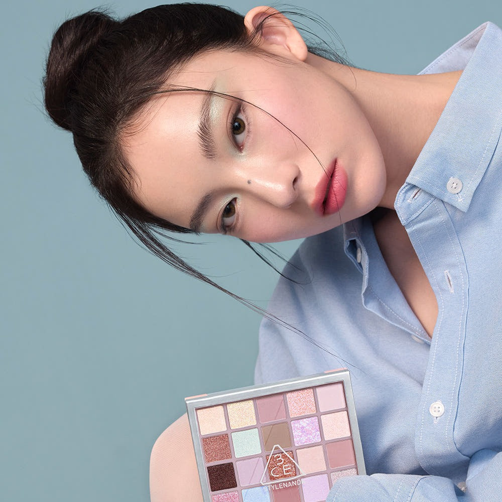 Décrivez l'image : 3CE XL Eyeshadow Palette de 3CE, maquillage yeux, tenue bleu, fond bleu, maquillage artistique.