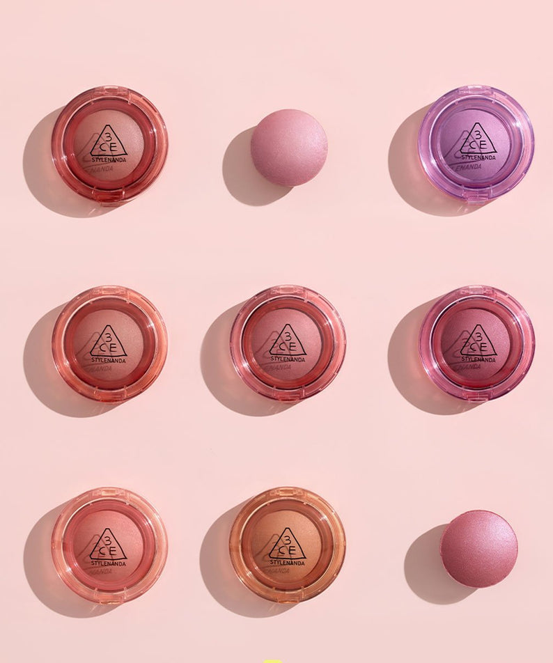 Collection de 3CE Bouncy Blur Balm sur fond rose, montrant des teintes variées pour un effet lissant et floutant sur la peau.