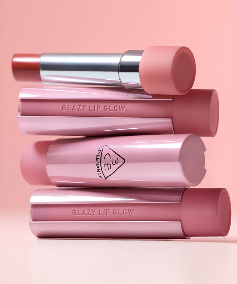 3CE Glaze Lip Glow 3.2g en rose élégant, tubes ouverts et fermés sur fond rose délicat.
