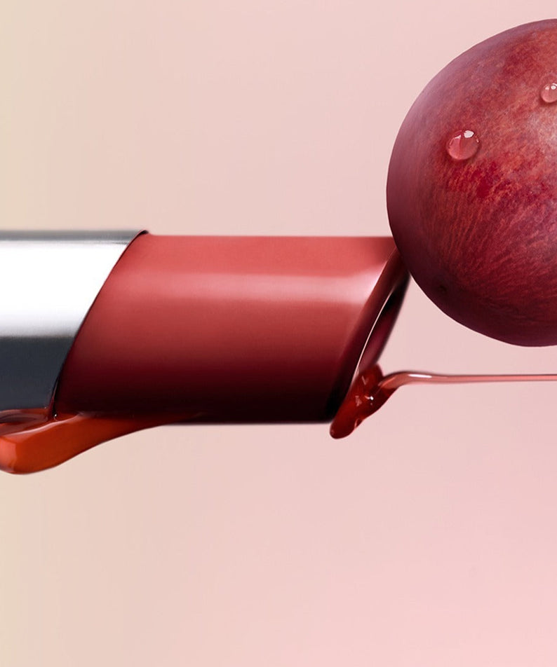 3CE Glaze Lip Glow 3.2g avec raisin et gouttes de rosée sur un fond doux et estompé.