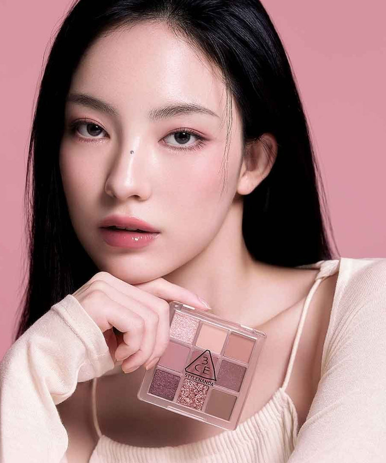 3CE Multi Eye Color Palette : maquillage des yeux, étui à côté du visage, modèle sur fond rose, produit 3CE