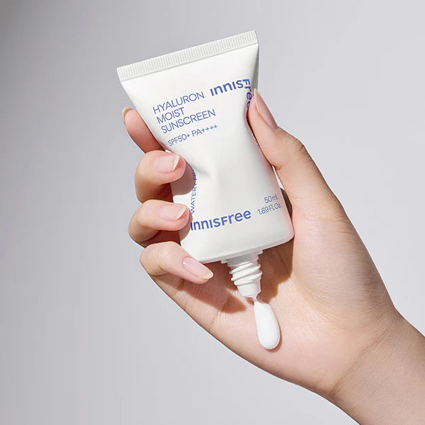 Main tenant INNISFREE Hyaluron Moist Sunscreen 50ml, tube blanc crème SPF, sur fond clair, produit beauté en gros plan.