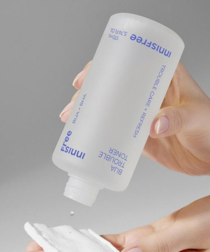 INNISFREE Bija Trouble Toner 170ml de la marque Innisfree, main versant une lotion sur peau, fond gris.