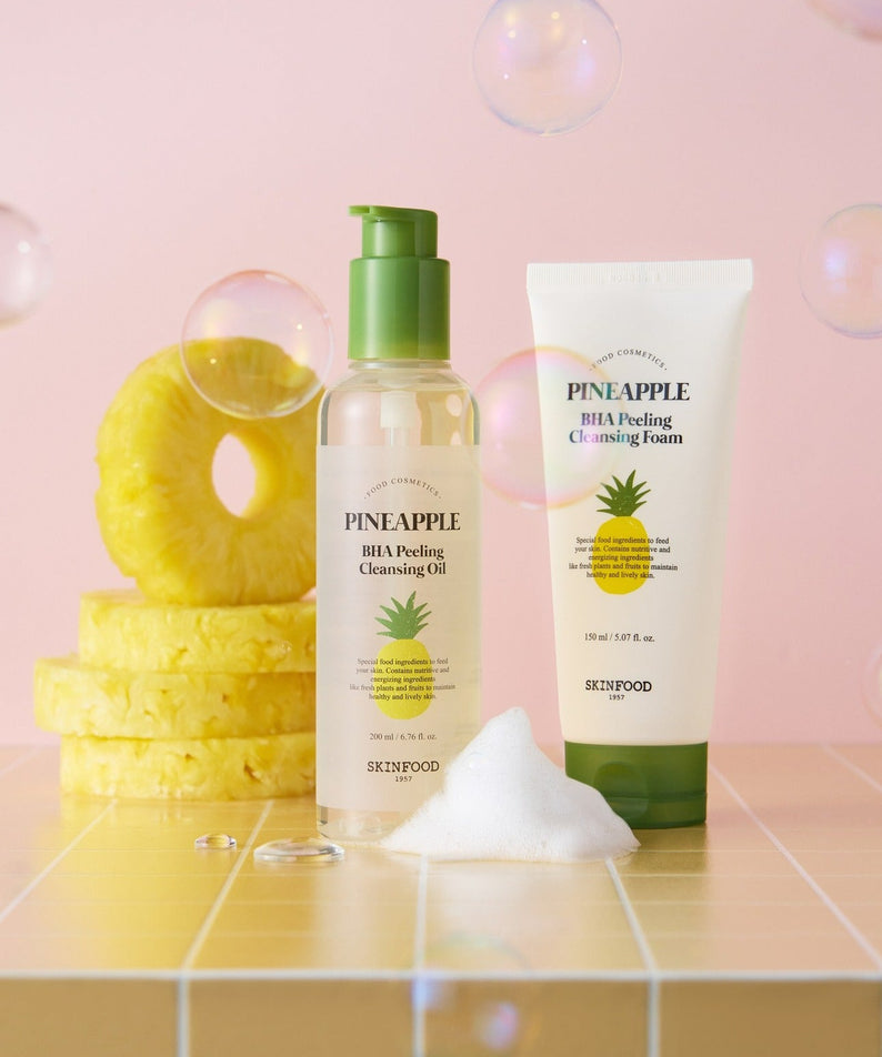 SKINFOOD Pineapple BHA Peeling Cleansing Foam 150ml de SKINFOOD, flacon et tube sur fond rose avec rondelles d’ananas