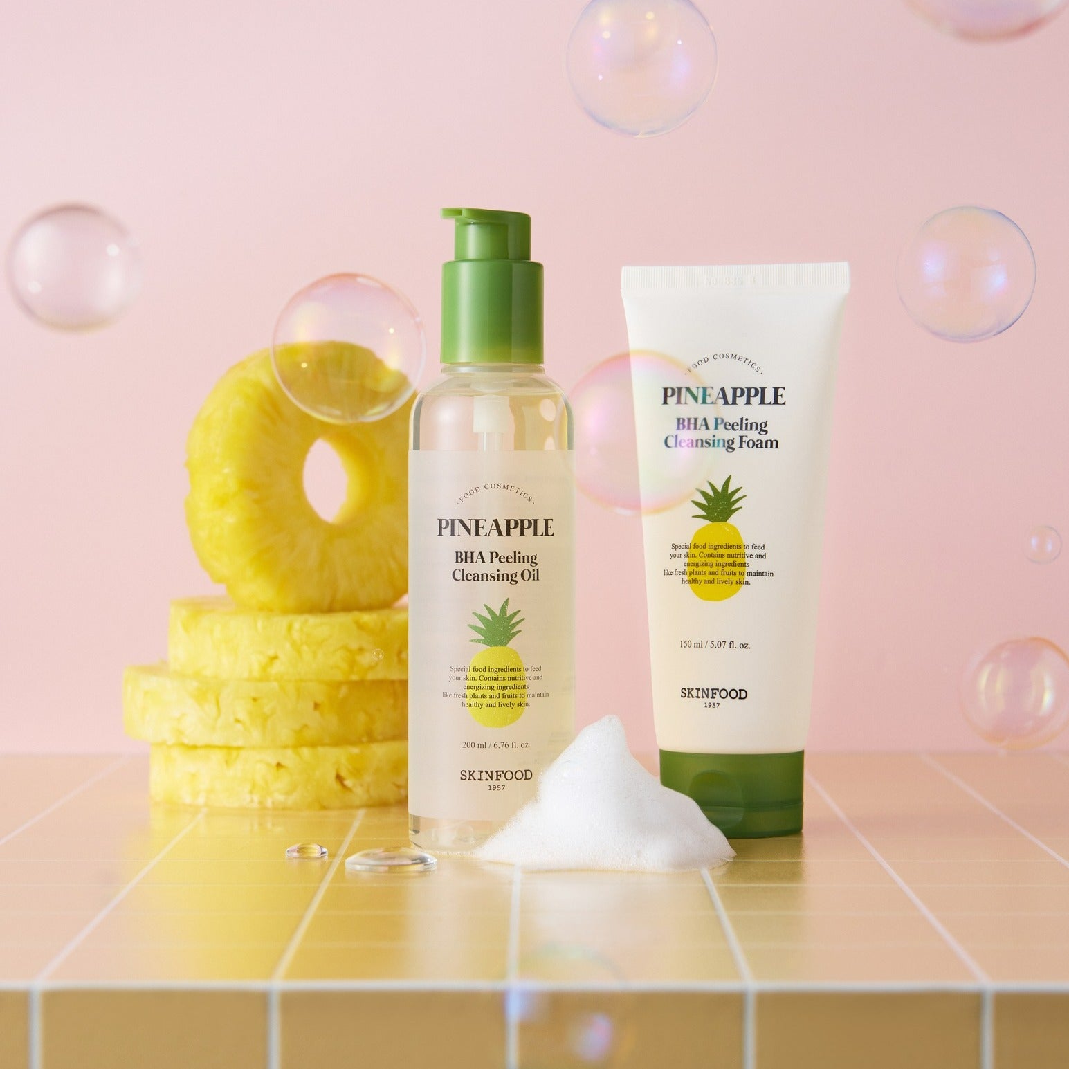 SKINFOOD Pineapple BHA Peeling Cleansing Foam 150ml de SKINFOOD, flacon et tube sur fond rose avec rondelles d’ananas