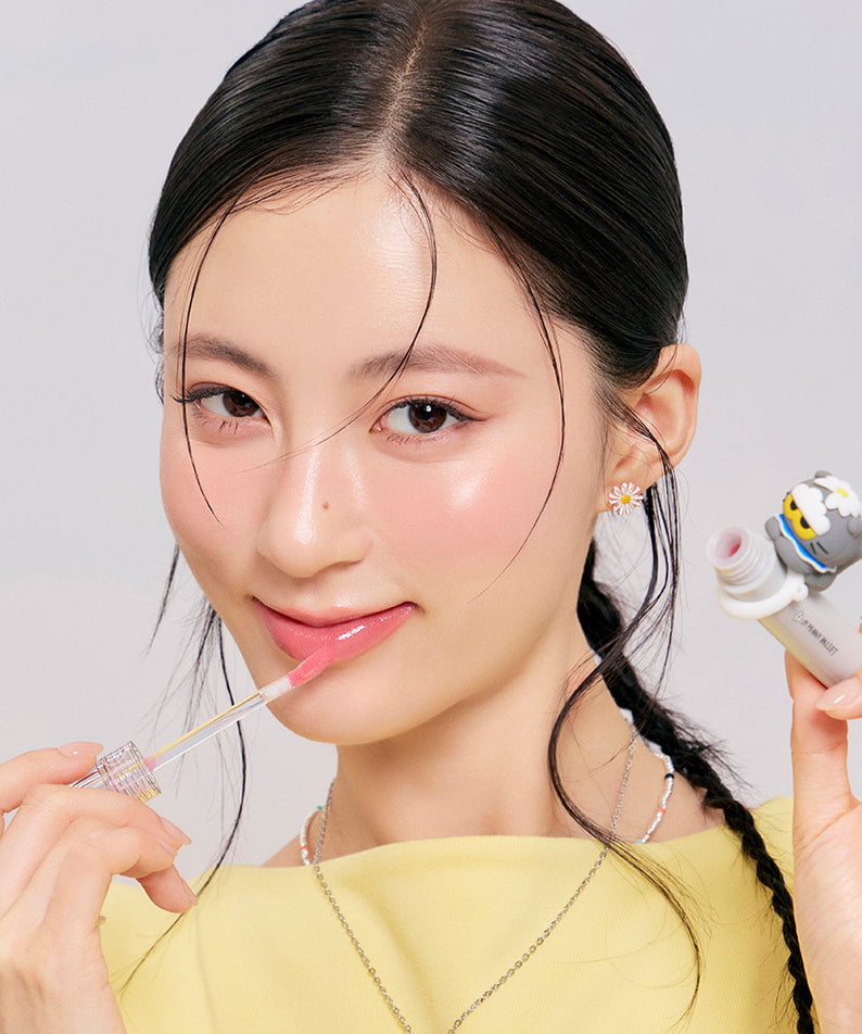 ROMAND x Joanne Friends Glasting Color Gloss appliqué par une femme souriante, couleur éclatante en vedette. Beauté et élégance.