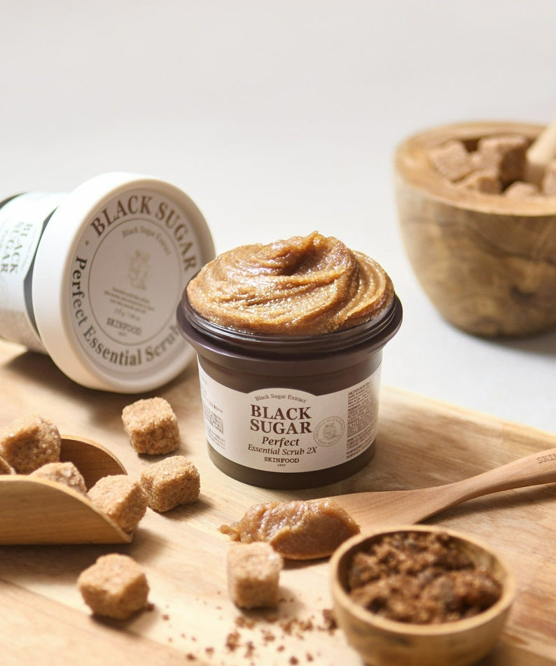 SKINFOOD Black Sugar Perfect Essential Scrub 2x 210g sur table bois, pot et ingrédients de gommage, contexte naturel
