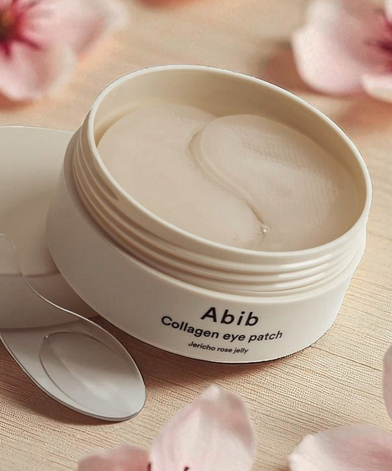 ABIB Collagen Eye Patch Jericho Rose Jelly 90g d’Abib, pot crème et patch sous fleurs roses, table beige.