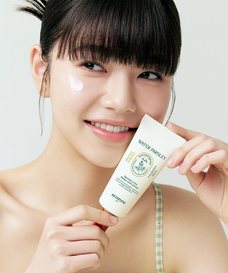 SKINFOOD Pantothenic Water Parsley Silence Essence 70ml, femme souriante applique le soin, fond clair, flacon vert.