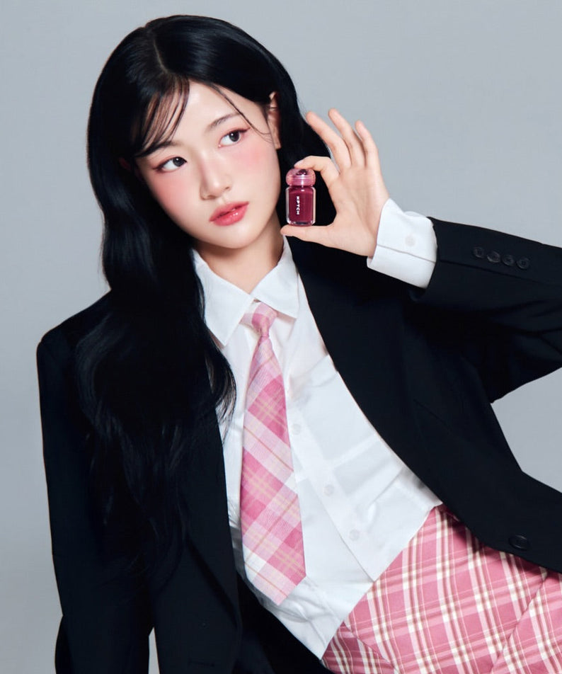 KEEP IN TOUCH Chili Jelly Lip Plumper de la marque KEEP IN TOUCH, femme en uniforme tenant le flacon, fond uni clair